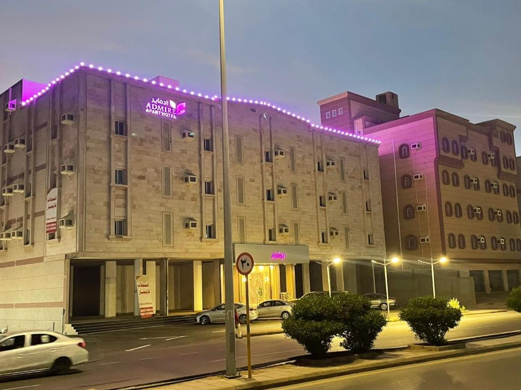 a building with purple lights on the side of it at Admire Apart Hotel - 1 in Abu Arish