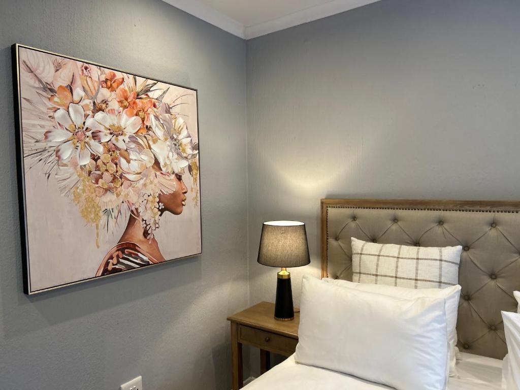 a bedroom with a picture of a woman with flowers on the wall at Hillsview, Roodepoort in Roodepoort