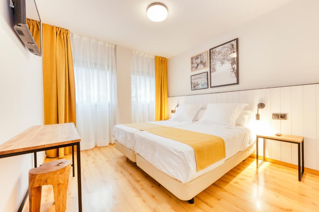 a bedroom with a large white bed and a table at Hotel Viella in Vielha