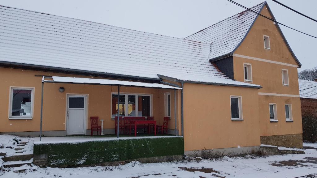 a yellow house with a porch in the snow at Ferienwohnung Freund & Berndt in Nermsdorf
