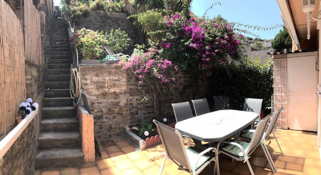 a table and chairs on a patio with flowers at Maison 90 m2, 5 min du Port, 15 min des Criques à Pied in Port-Vendres