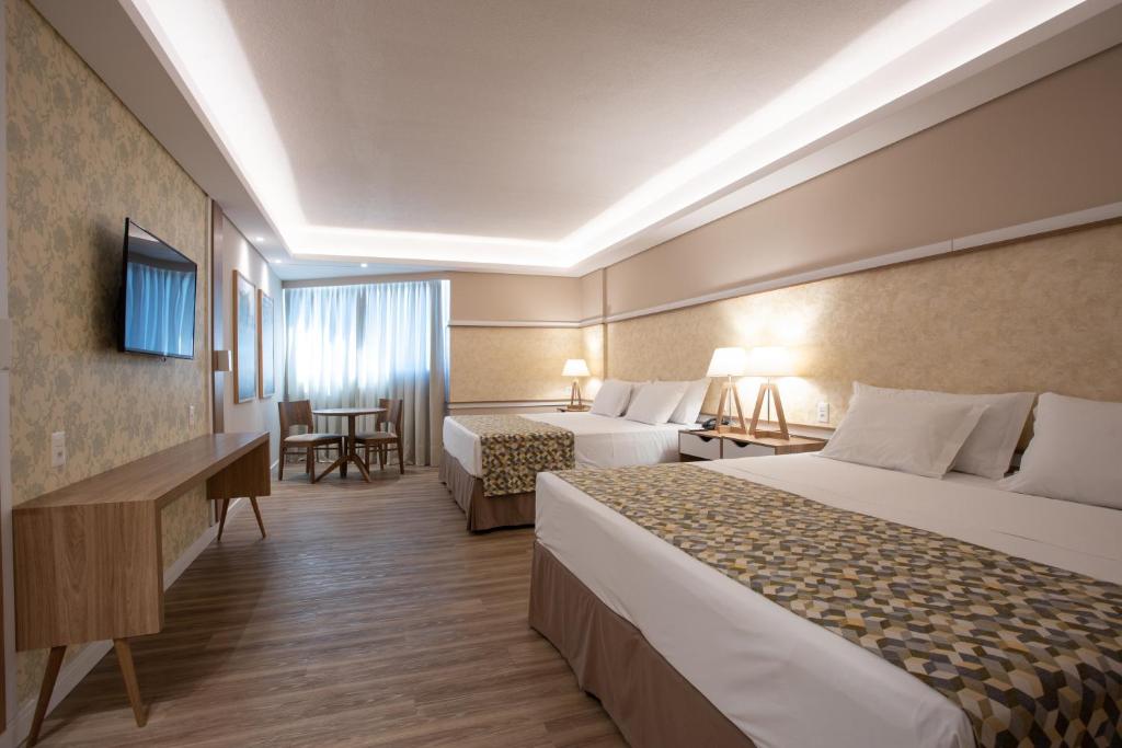 um quarto de hotel com duas camas e uma secretária em Recanto Cataratas - Thermas, Resort e Convention em Foz do Iguaçu