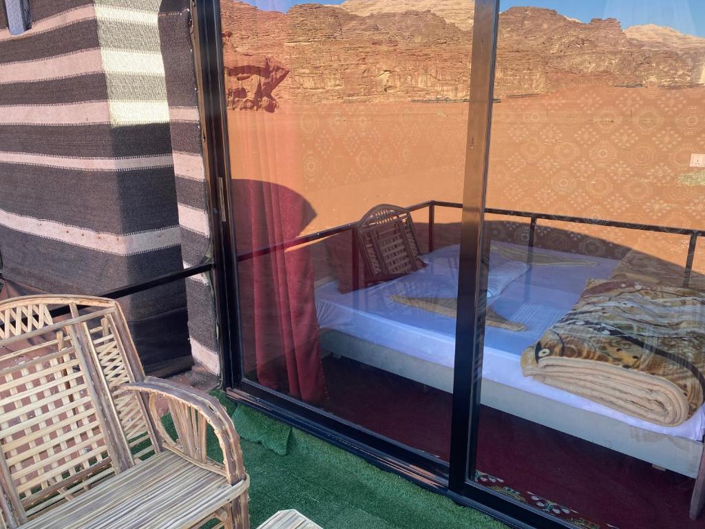 a room with a bed and a chair on a balcony at Desert shine camp in Wadi Rum