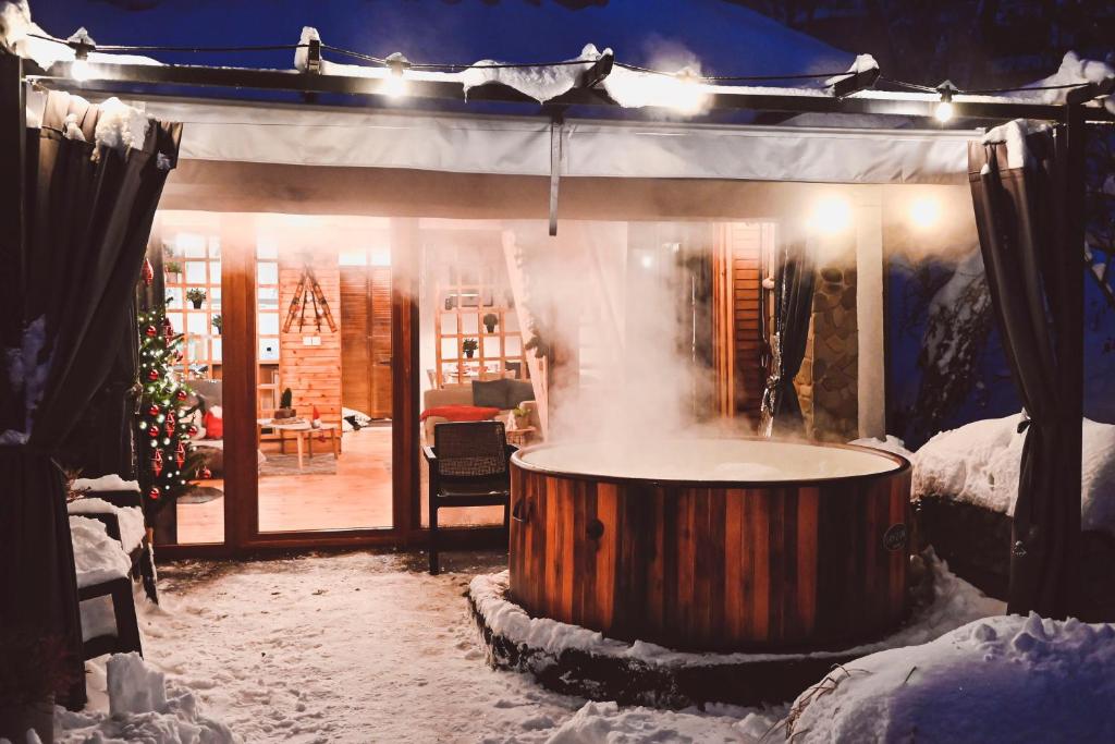 una vasca idromassaggio in una casa con neve e luci di STRÓŻÓWKA SKI&SPA Domek nad rzeką z ogrodem i jacuzzi,narty. a Stróża