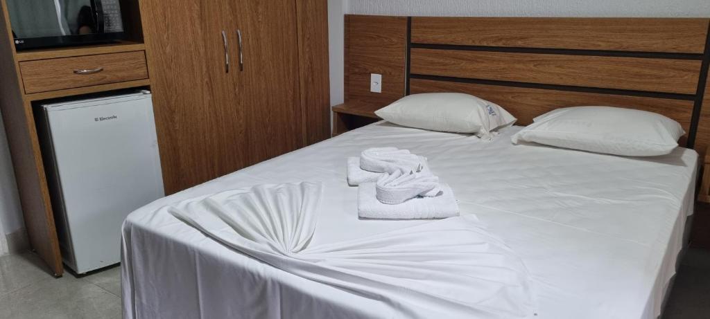 1 dormitorio con 1 cama con sábanas y almohadas blancas en ARARAS Apart Hotel - CTC, en Caldas Novas