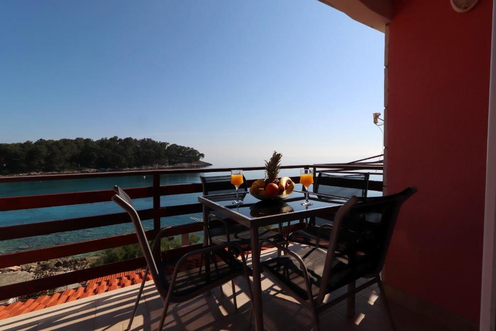stół i krzesła na balkonie z widokiem na wodę w obiekcie Apartments Prižba Bay w mieście Prižba
