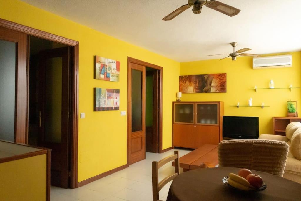 ein Wohnzimmer mit gelben Wänden und einem Tisch in der Unterkunft Cómodo apartamento en el centro - Gran Vía in Madrid