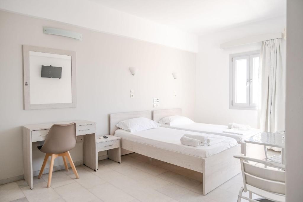a white bedroom with two beds and a desk at Korali Garden in Naxos Chora
