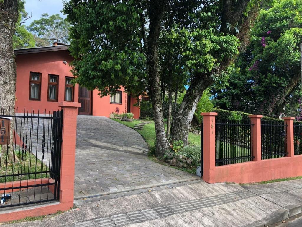 una cerca frente a una casa roja en Estúdio Palace Hotel Canela, en Canela