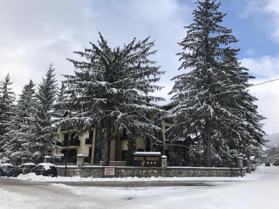 a building with snow covered trees in front of it at Hotel Pagnani in Pescasseroli
