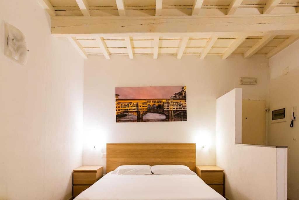 een slaapkamer met een bed en een schilderij aan de muur bij Lovely studio steps from Basilica Santa Croce in Florence