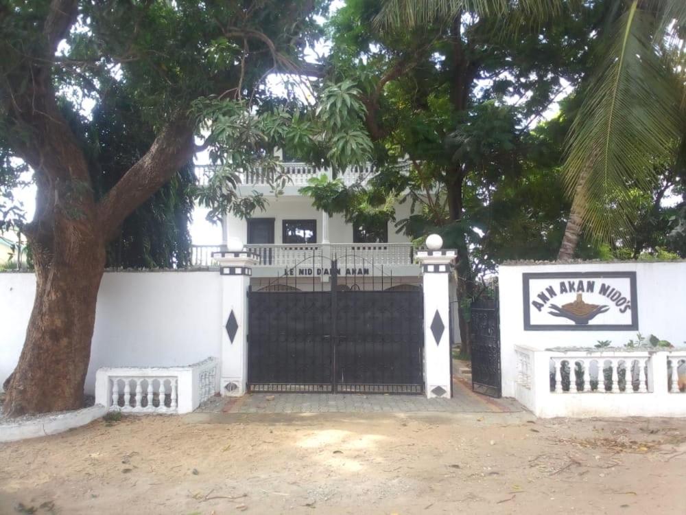 ein weißes Haus mit einem schwarzen Tor und einem Baum in der Unterkunft ANN AKAN NIDO’S in Malindi