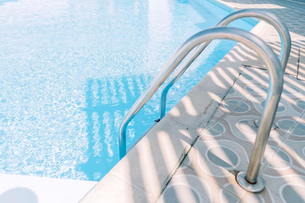 a swimming pool with a metal handrail next to the water at Korali Garden in Naxos Chora