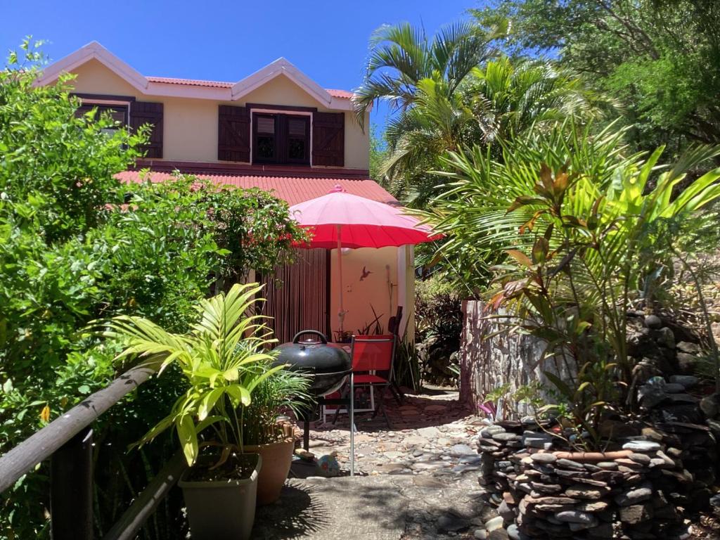 a house with a red umbrella and a table at A Ka Foufou La in Bouillante