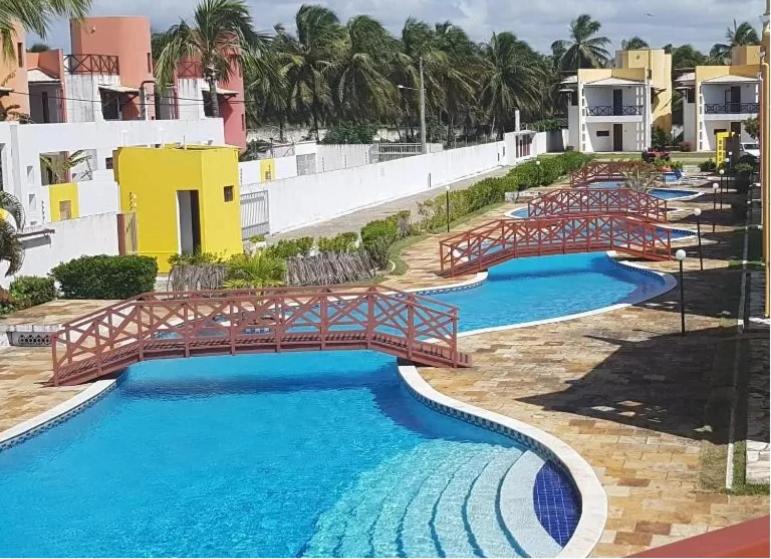 a swimming pool with a bridge in a resort at Paraiso de Maracajau in Maracajaú