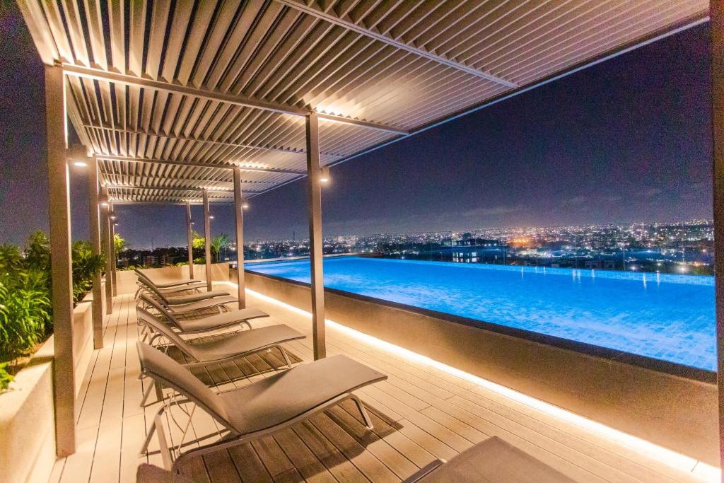a deck with lounge chairs and a pool at night at Accra Luxury Apartments @ The Lennox in Accra
