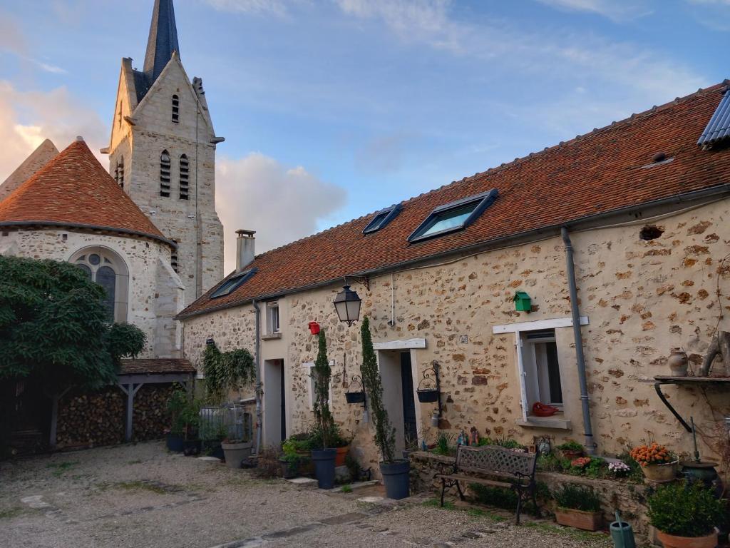 un antiguo edificio de piedra con una iglesia en el fondo en le Portail bleu, en Châtres