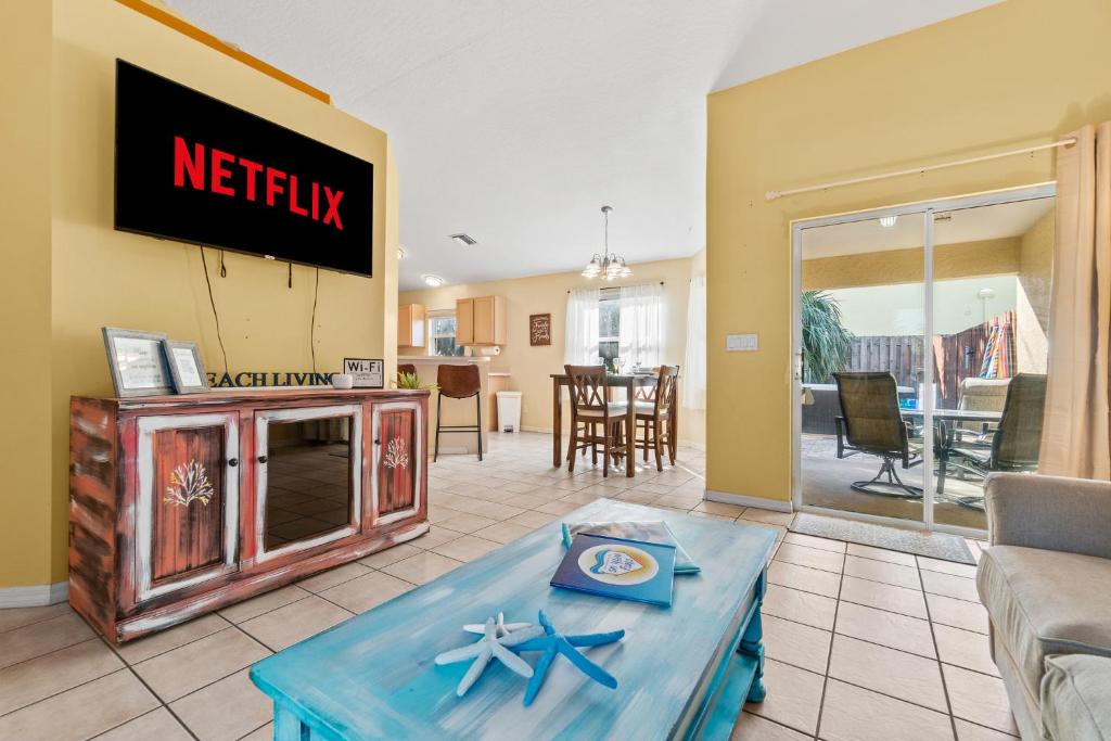 a living room with a table and a television at Heart of the Waves - 3BR & 2BA Beach Retreat - NEW HOT TUB - Outside Patio with Grill & Seating, Steps to Fun! in Melbourne