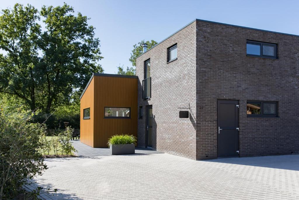 a brick building with a garage and a door at Vakantiehuis Eikzicht gelegen aan het bos in Elsloo