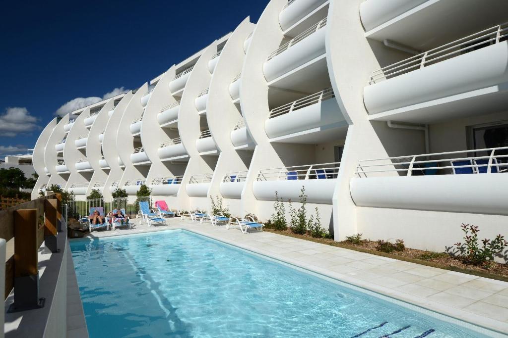 un hotel con piscina frente a un edificio en Résidence Odalys Les Dunes du Soleil en La Grande-Motte