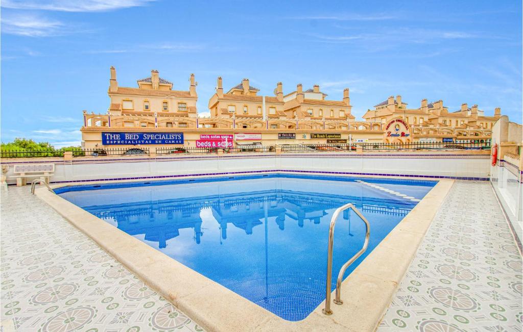 a swimming pool in front of a large building at Stunning Apartment In Orihuela Costa With Outdoor Swimming Pool in Playas de Orihuela