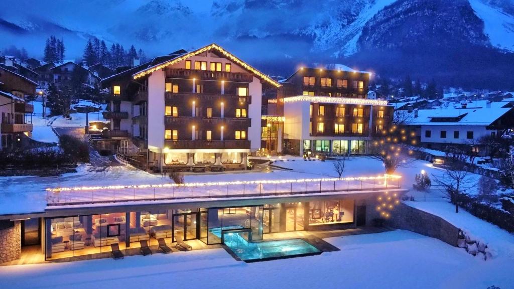 un hotel en la nieve por la noche con luces en Parkhotel Ladinia, en San Vito di Cadore