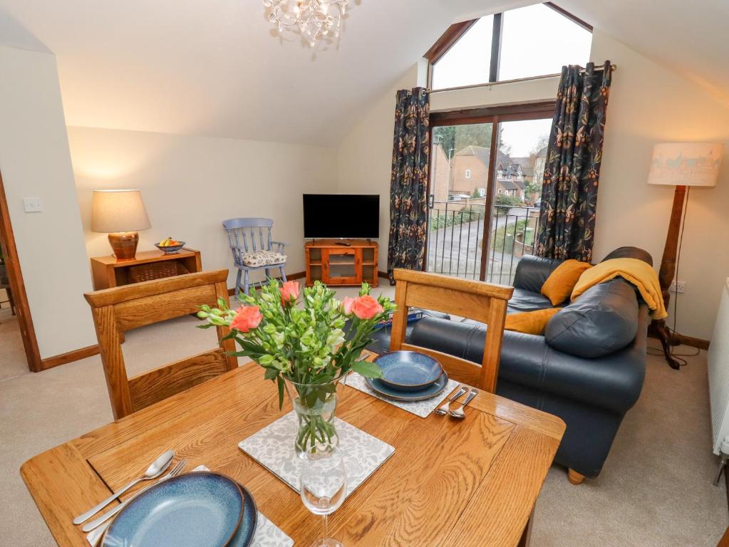 uma sala de estar com uma mesa e um sofá em The Coach House em Cheltenham