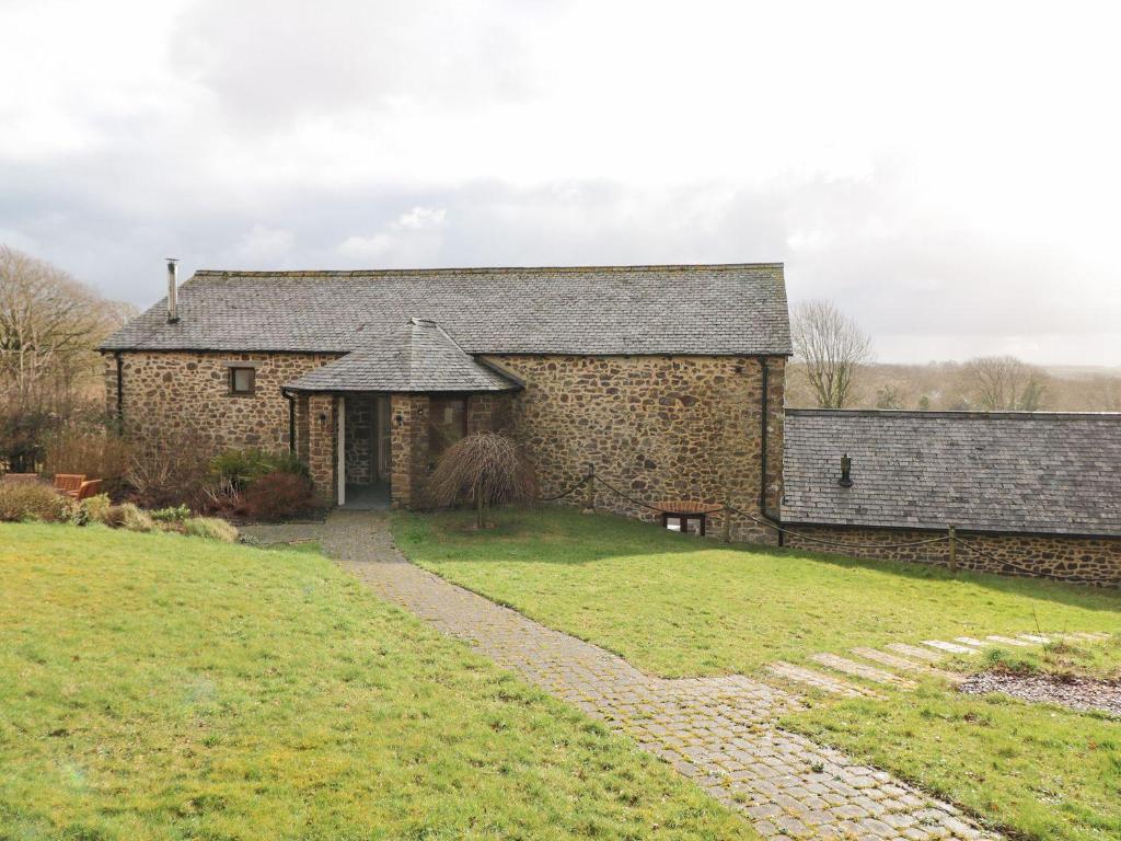 an old stone building with a grassy yard at Hoppers Barn in Holsworthy