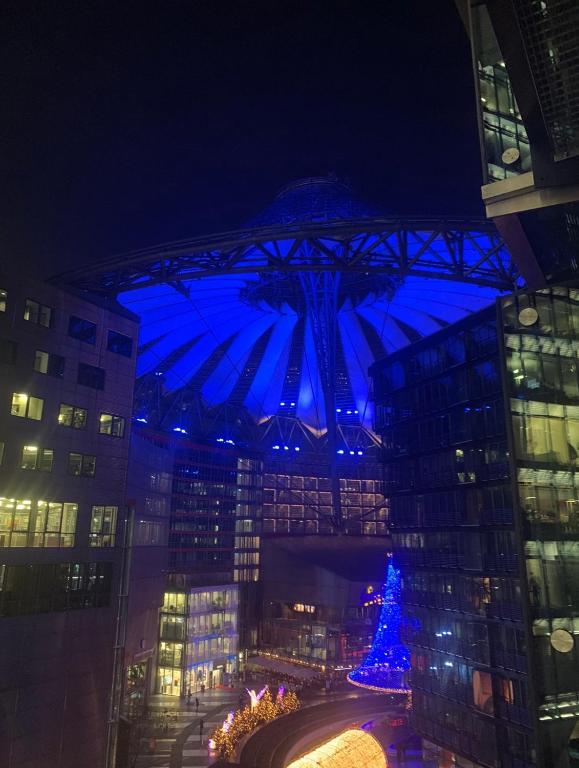 un árbol de Navidad frente a un edificio con luces azules en Fairytale in Sony Center Berlin, en Berlín