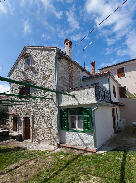 a stone house with green shutters on a building at Holiday Home Mihovilovic in Premantura