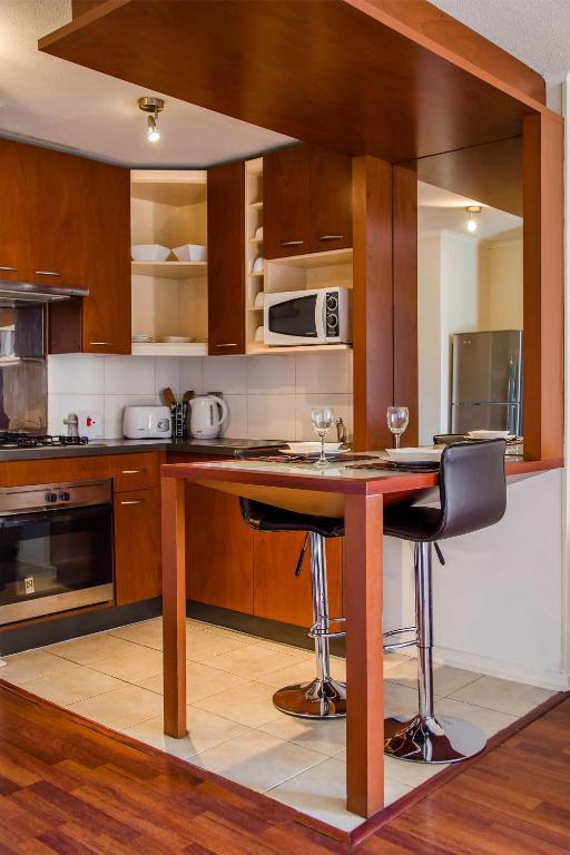 a kitchen with a table and two bar stools at San Ignacio Suite Apartments in Santiago