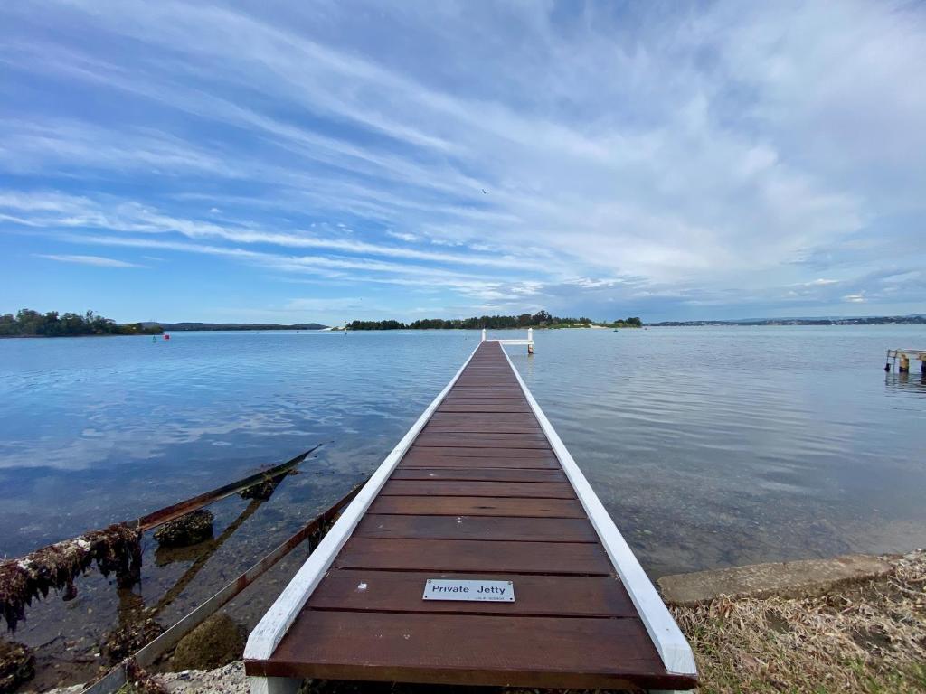 a wooden dock in the middle of a body of water at Serenity by the Lake - Romantic Waterfront Couple's Getaway in Marks Point