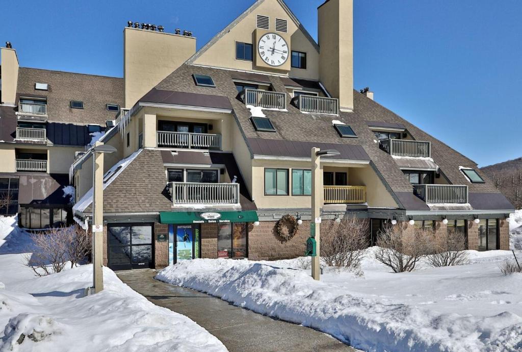 a large building with a clock on it in the snow at Mountain Green Resort by Killington VR - 2 Bedrooms in Killington