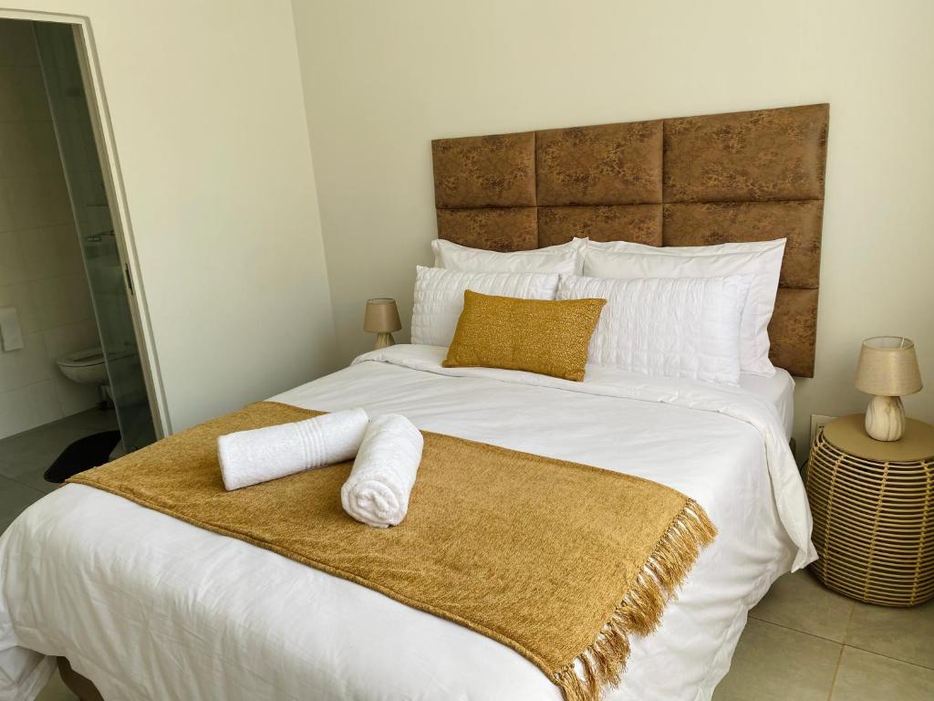 una camera da letto con un grande letto bianco con asciugamani sopra di Zimbali Lakes Boulevard Royal Suite 116 a Ballito