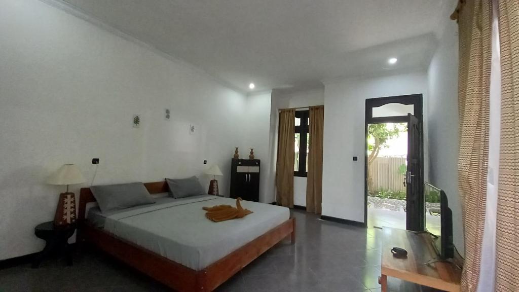 1 dormitorio con 1 cama y TV en Gili Welldone Guesthouse, en Gili Trawangan