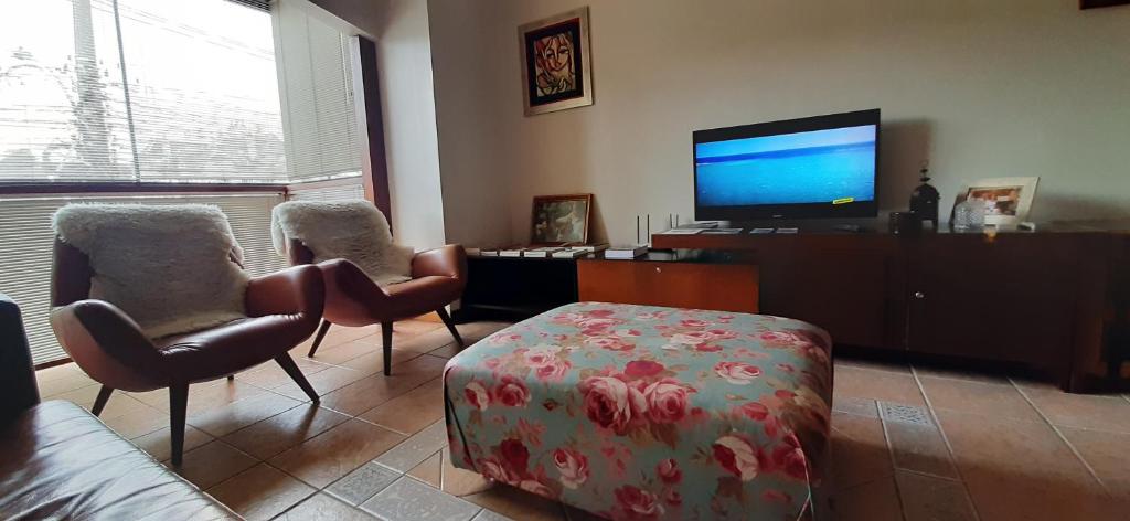 sala de estar con 2 sillas y TV de pantalla plana en ap 101, en Gramado