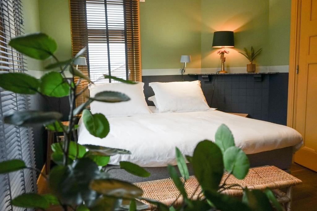 a bedroom with a bed with a plant in the foreground at Villa la Vida in Tilburg