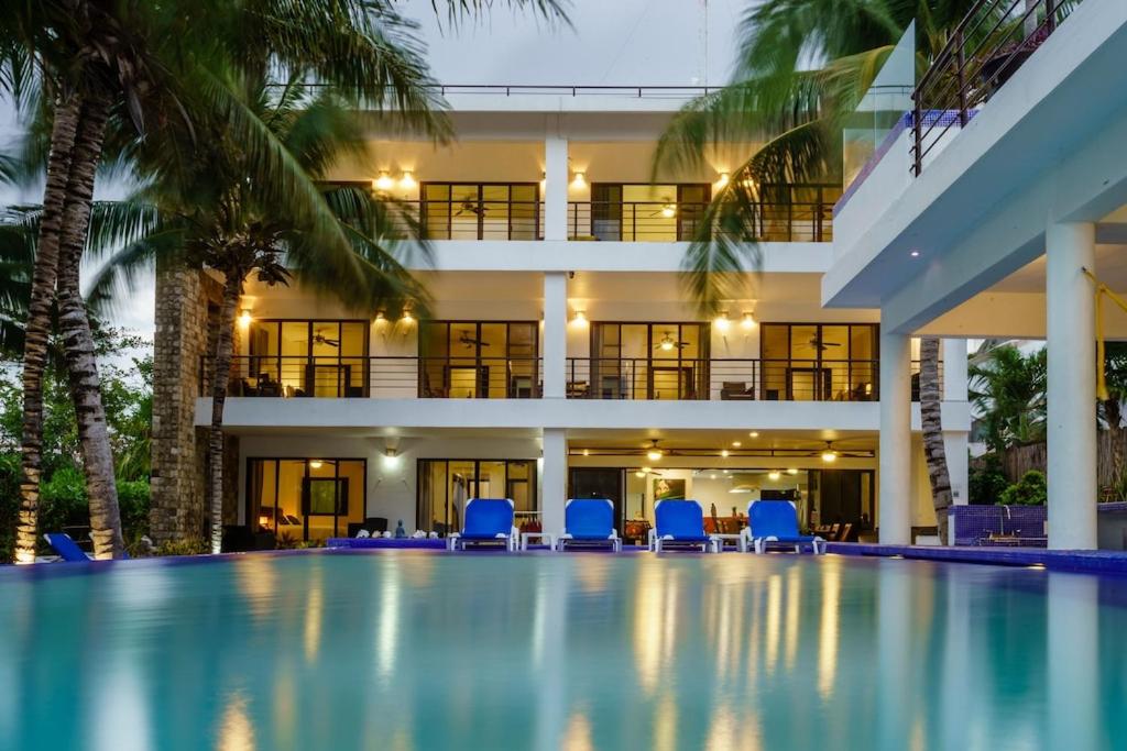 - une piscine en face d'un bâtiment avec des chaises bleues dans l'établissement Villa Bellamar : A dream beachfront spot near Tulum with Chef Service included, à Akumal