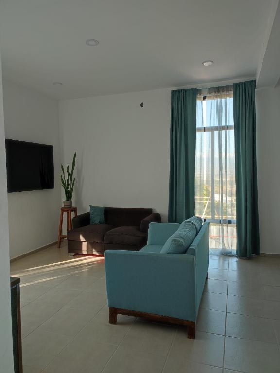 a living room with a blue couch and a television at LOMAS AEROPUERTO in San Agustin de las Juntas