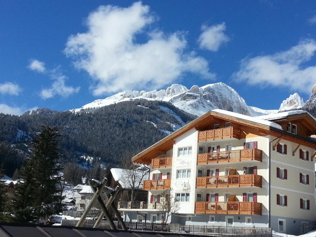 un hotel con montañas cubiertas de nieve en el fondo en Residence Ciasa Alpe, en Vigo di Fassa