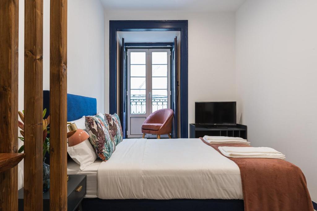 a bedroom with a bed and a chair and a window at Succeed Terreiro do Paço Suites in Lisbon