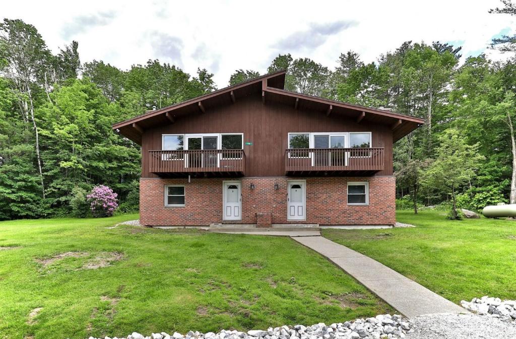 a brick house with a balcony on a yard at Breakaway House by Killington Vacation Rentals in Killington