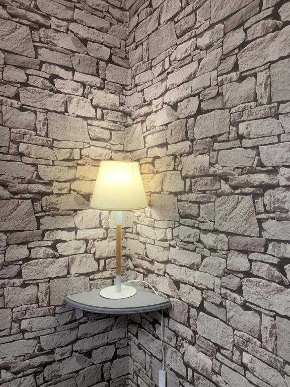 a lamp on a table in front of a stone wall at Au Coeur De Lyon in Lyon