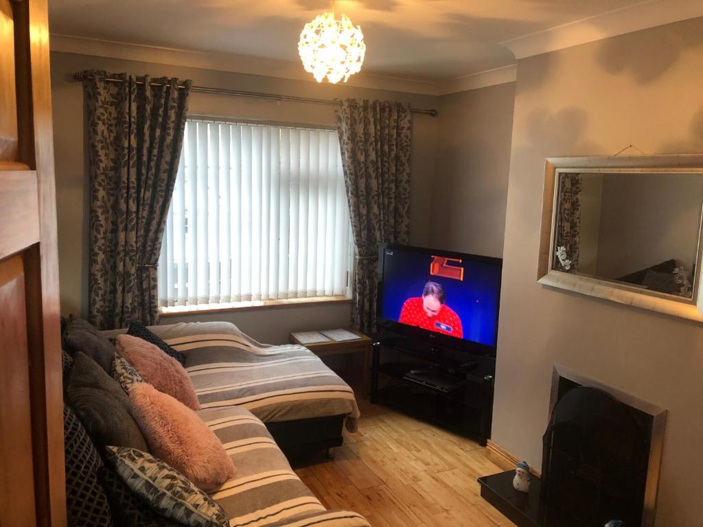a living room with a couch and a tv at Moville Centre Apartment in Moville