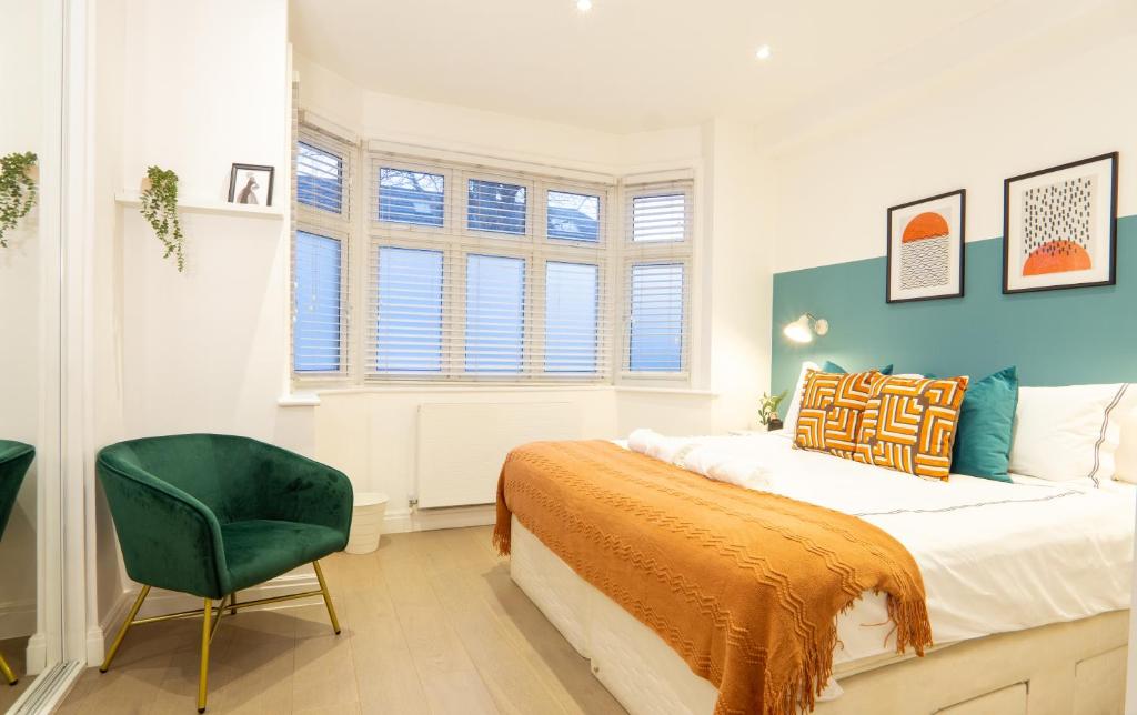 A beautiful one bedroom flat with garden & parking في ميل هيل: غرفة نوم بسرير وكرسي أخضر