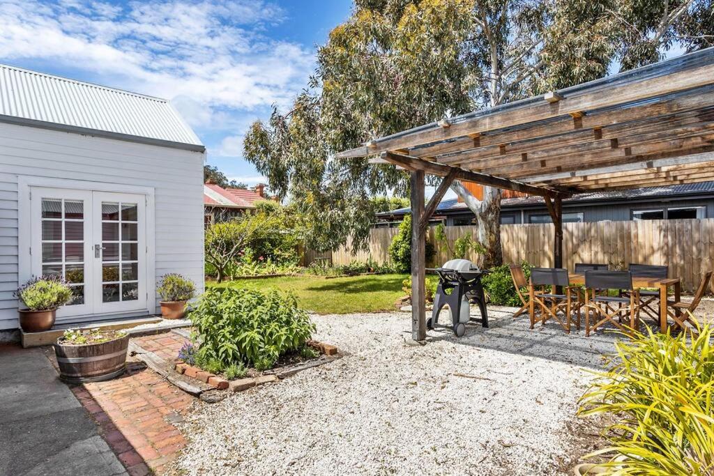 a backyard with a picnic table and a wooden pergola at 'Balmoral Cottage' A Kingston Beach Escape in Kingston Beach