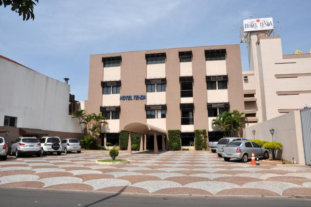 un gran edificio con coches estacionados en un estacionamiento en Hotel Tenda, en Marília