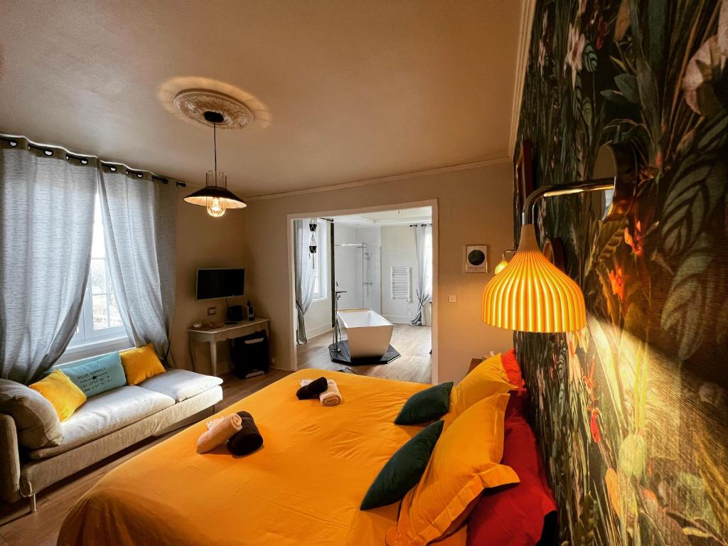 - une chambre avec un grand lit jaune et un canapé dans l'établissement L'ESCALE Chambres et table d'hôtes, à Verdun-sur-le-Doubs