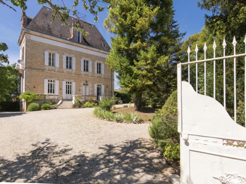 a gate in front of a large house at Le Petit Chateau in Brouchaud