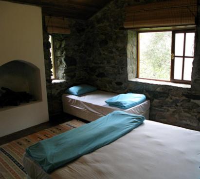 1 dormitorio con 2 camas en una habitación de piedra con 2 ventanas en zerguz camping, 